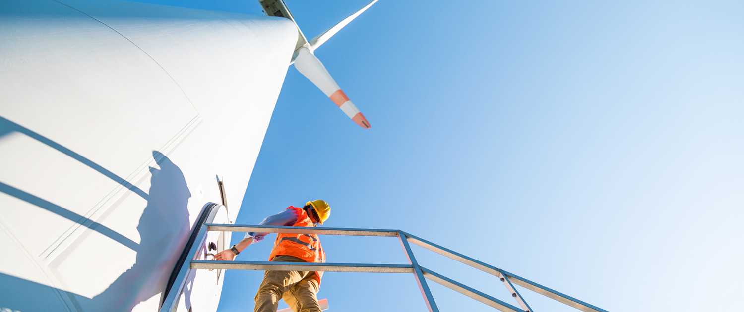 Ingegnere con gilet e caschetto fa manutenzione alla turbina eol